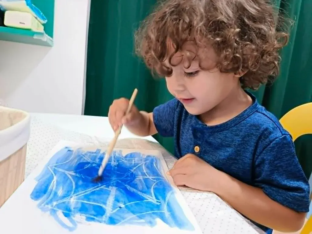 A student drawing an art project with a spiderweb design