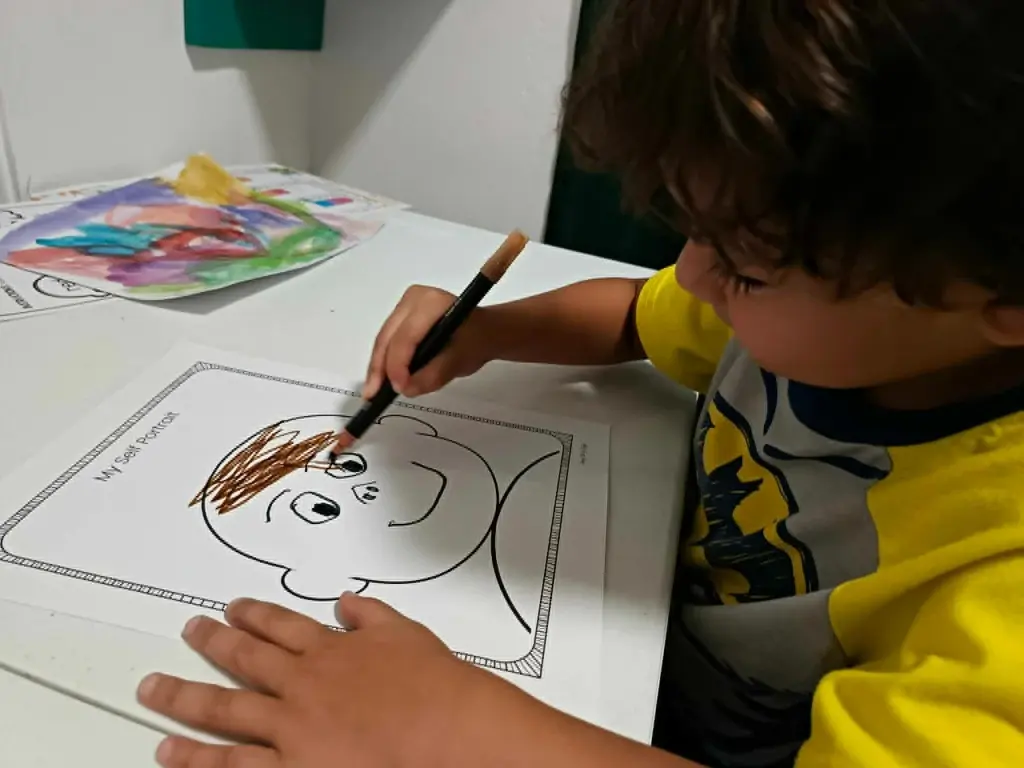 A student showing a self-portrait drawing